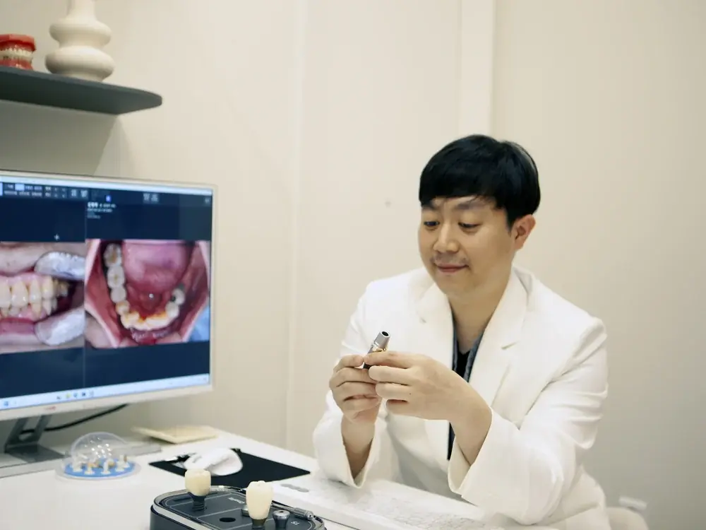 모니터에 구강 사진을 띄우고 치료 계획을 설명하는 원장
