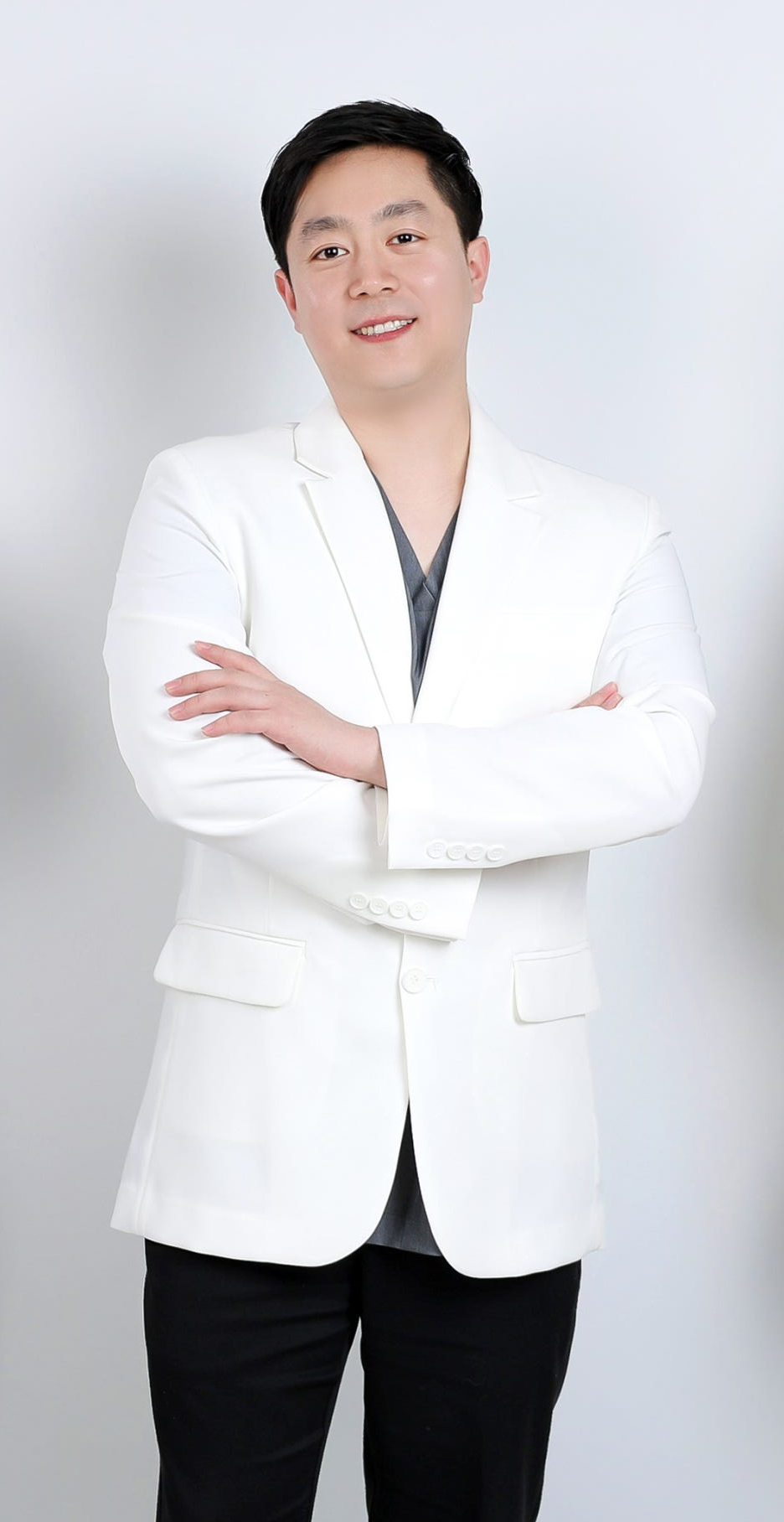 흰색 의사 가운을 입고 팔짱을 낀 채 정면을 보고 미소 짓는 남성 의사
