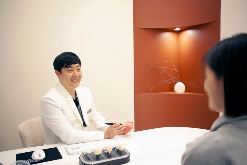 치과 의사가 환자와 상담하며 치아 모형을 보여주는 모습