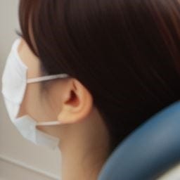 마스크를 착용한 환자가 치과 유닛 체어에 앉아있는 모습