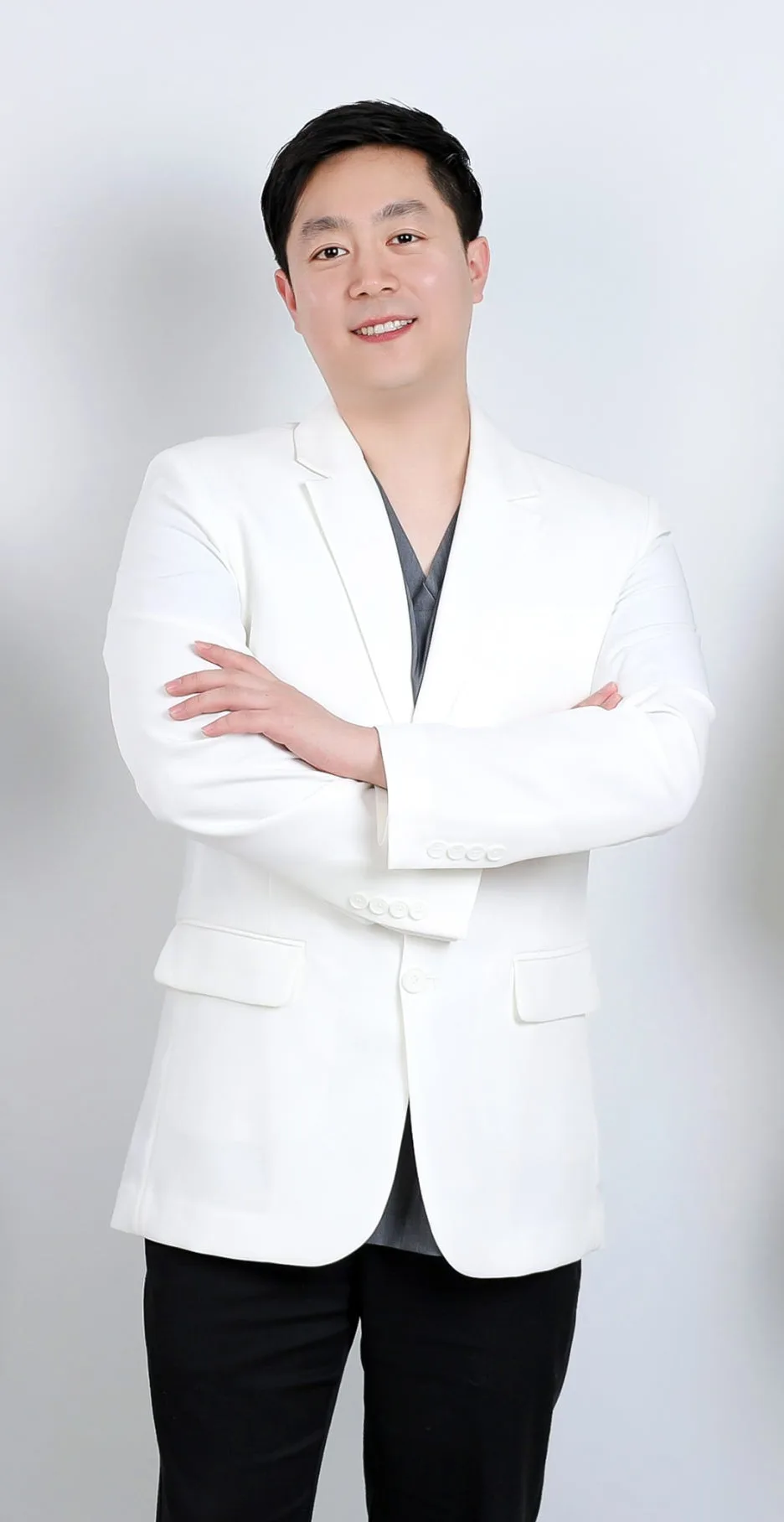 하얀색 의사 가운을 입고 팔짱을 낀 채 정면을 보고 미소 짓는 남자 의사